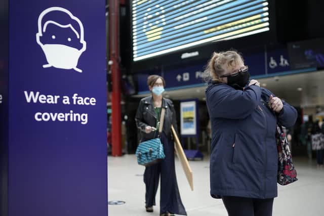 People wear face masks at the train station on July 14, 2020 in Liverpool. The UK government has announced that people entering shops will be required to wear a face mask by law from July 24. (Photo by Christopher Furlong/Getty Images)