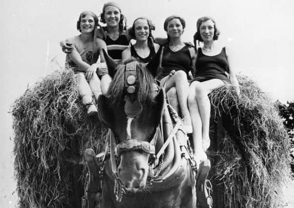 30th June 1934:  Girls in bathing costumes ride home on a load of hay after helping out with the harvest, at Torquay.  (Photo by Fox Photos/Getty Images)