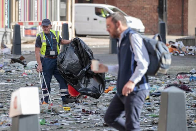 Workers clear litter in the centre of Leeds after celebrations by fans whose football club won the Championship title and a return to the Premier League.