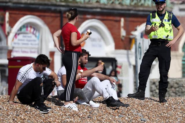 An officer advises people to leave the beach in Brighton as the UK continues in lockdown. Gareth Fuller/PA Wire