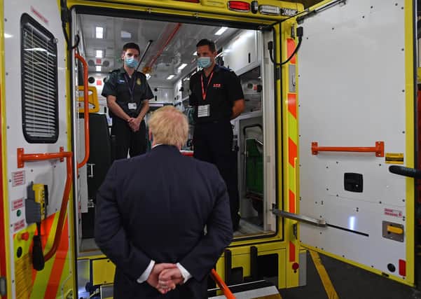 Boris Johnson (C), talks with brothers paramedic a paramedic Jack Binder (L) and firefighter Tom Binder, standing inside the back of an ambulance, during his visit to the headquarters of the London Ambulance Service NHS Trust earlier this month.