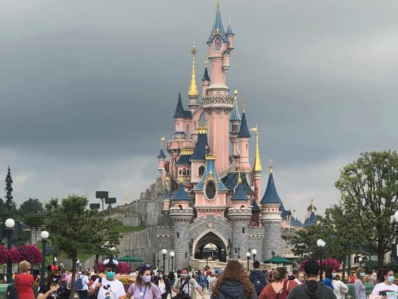 Masked visitors in front of Sleeping Beauty Castle at Disneyland Paris. (Picture: PA).