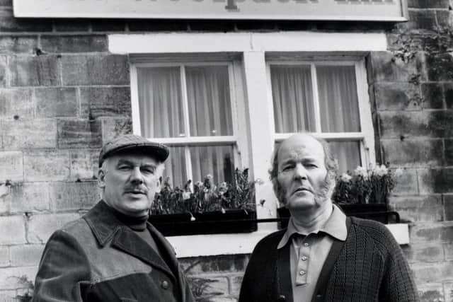 Yorkshire TV's "Emmerdale Farm" characters Mr Wilks (Arthur Pentelow) and Amos Brearley (Ronald Magill) standing outside the original Woolpack Inn in Esholt, near Bradford