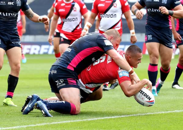 Salford Red Devils' Tuimoala Lolohea scores his side's second try as he's tackled by Hull FC's Josh Jones (left).