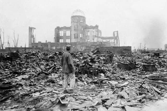 In this Sept. 8, 1945 file photo, an allied correspondent stands in the rubble in front of the shell of a building that once was a exhibition center and government office  in Hiroshima, Japan, a month after the first atomic bomb ever used in warfare was dropped by the U.S. on Aug. 6, 1945. (AP Photo/Stanley Troutman)