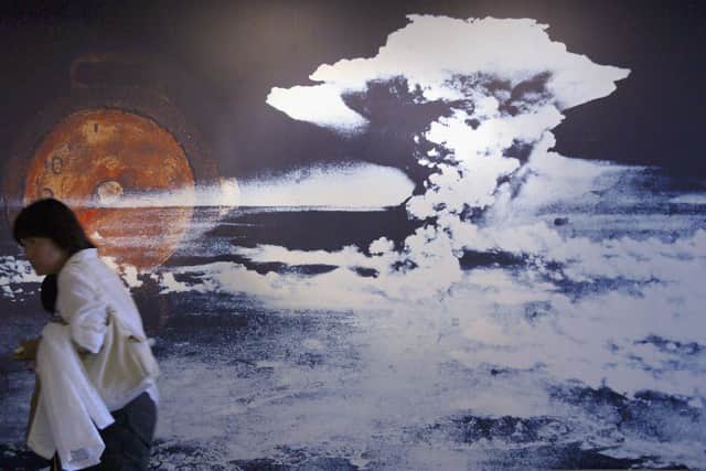 A visitor passes by a wall displaying a picture of the mushroom cloud pictured when the atomic bomb was dropped on August 5, 1945 in Hiroshima, Japan. (Photo by Junko Kimura/Getty Images)