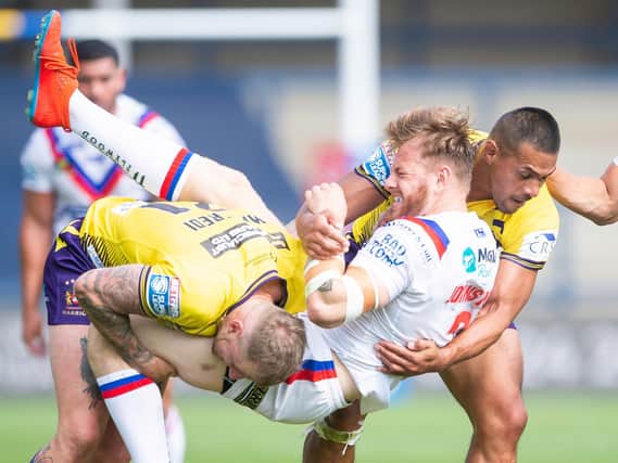 Wakefield Trinity's Tom Johnstone is tackled by Dom Manfredi an Willie Isa in the game against Wigan. (Allan McKenzie/SWpix.com)