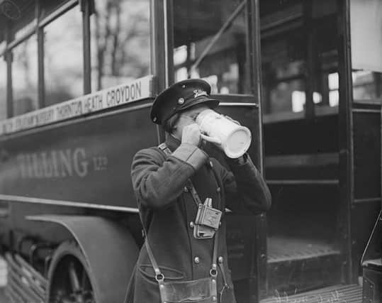 February 1916:  Standing beside her bus a woman bus conductor is drinking hot milk  from a large mug.  (Photo by Topical Press Agency/Getty Images)