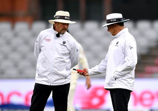 Bad light: Umpires take a light reading during day one of the first Test at Old Trafford, Manchester. Picture: PA