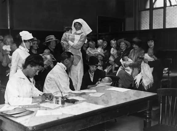 circa 1921:  A doctor examining infants at the children's department of St Thomas' Hospital.  (Photo by Topical Press Agency/Getty Images)
