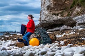 Donna Blyth, wearing and holding a half finished knitted traditional gansey, on the shore of South Landing at Flamborough. By James Hardisty.