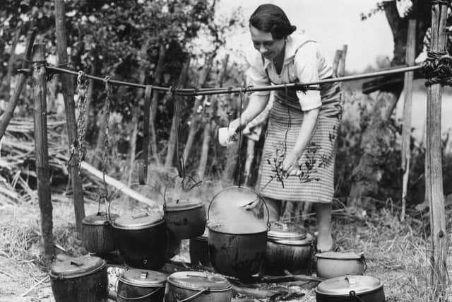 29th August 1937:  A woman preparing a meal for hop pickers at the Whitbread hop camp in Paddock Wood, Kent.  (Photo by Fred Morley/Fox Photos/Getty Images)