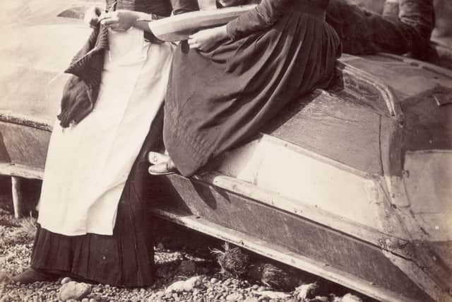 circa 1880:  A group sitting on an upturned boat, with a girl knitting.  (Photo by Frank Meadow Sutcliffe/Getty Images)