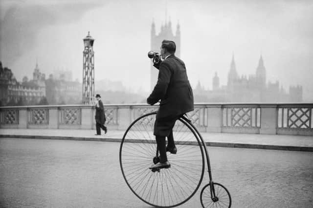17th October 1932:  Edwin Davey, riding a penny farthing bicycle over Lambeth bridge in London, and blowing a bugle to warn of his approach.  (Photo by Fox Photos/Getty Images)