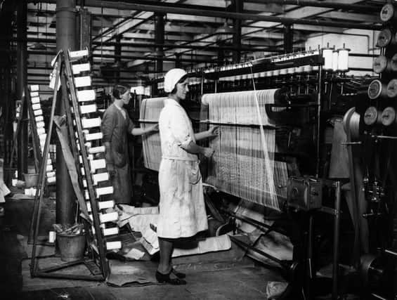 1934:  A textile worker operates an automatic spooling machine in a British thread mill.  (Photo by A. Hudson/Topical Press Agency/Getty Images)