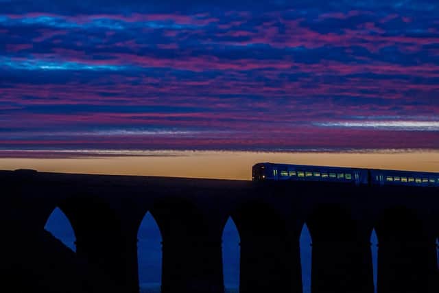 A Northern train passes over Ribblehead Viaduct at dusk