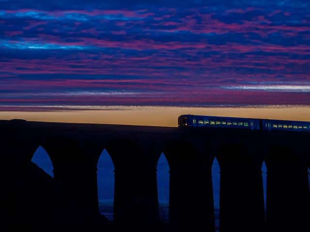 A Northern train passes over Ribblehead Viaduct at dusk