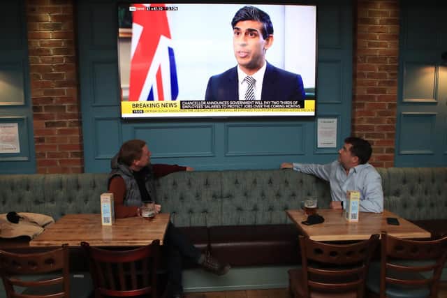 Customers in the Tib Street Tavern in Manchester watch as Chancellor of the Exchequer Rishi Sunak announces the government will pay two thirds of the wages of staff in pubs, restaurants and other businesses if they are forced to close under new coronavirus restrictions. Pic: PA