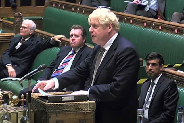 Boris Johnson addresses MPs as a grim-faced Rishi Sunak, the Chancellor, looks on.
