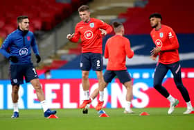 Missing out: England's Harry Winks, the unavailable Kieran Trippier and Tyrone Mings warm up. Picture: PA