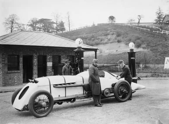 Welsh engineer and racing driver J. G. Parry-Thomas (1884 - 1927, centre) waits while his car, 'Babs', is filled with petrol at Brooklands motor racing circuit in Surrey, 23rd April 1926. The car, which is powered by a 27-litre Liberty aero-engine, is undergoing tests in preparation for a world speed record bid at Pendine Sands. (Photo by E. Bacon/Topical Press Agency/Hulton Archive/Getty Images)