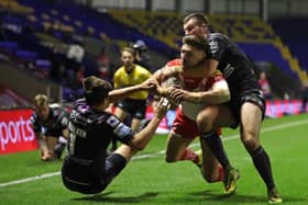 St Helens' Tommy Makinson (centre) powers through the tackles from Wakefield Trinity's Max Jowitt (right) and Alex Walker to score a try.