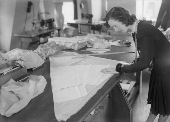 circa 1935:  A woman cuts out pieces of silk for an item of underwear using a paper pattern.  (Photo by General Photographic Agency/Getty Images)