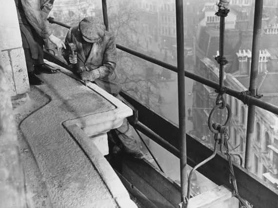A stonemason channelling the cornice on the roof of St Paul's Cathedral prior to fitting a covering of asphalt over the stone to preserve it as well as preventing water from falling onto stonework below, in the City of London, England, 23rd January 1934. (Photo by Fox Photos/Hulton Archive/Getty Images)