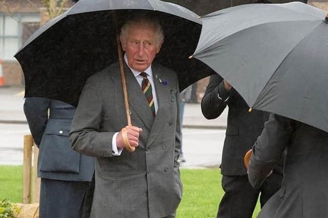 The Prince of Wales shelters from the rain at Menwith Hill.