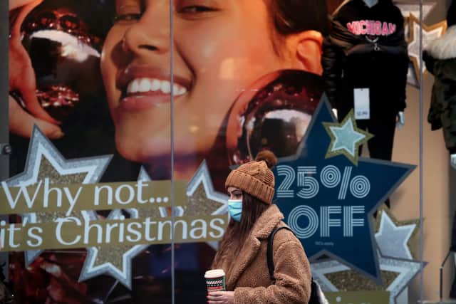 A person wearing a face covering walks passed a shop window displaying Christmas offers. Picture: Andrew Milligan/PA