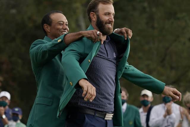 Over to you: Tiger Woods helps Masters' champion Dustin Johnson with his green jacket after his victory at Augusta. (AP Photo/Charlie Riedel)
