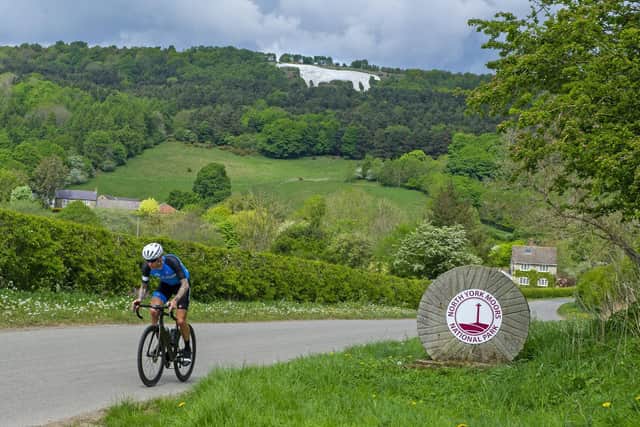 A cyclist exercises in the warm weather in the shadow of The White Horse of Kilburn in the Hambleton district near Thirsk, North Yorkshire