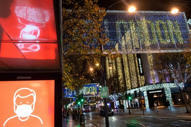 A screen advising the wearing of face masks is seen alongside Christmas lights on Oxford Street in central London, as England continues a four week national lockdown. Picture: Dominic Lipinski/PA Wire