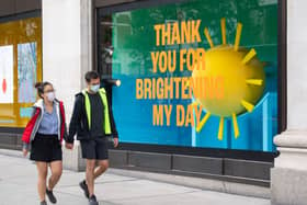 Two people wearing protective face masks pass window dispays at Selfridge's on Oxford Street, London in June. Picture: Dominic Lipinski/PA Wire