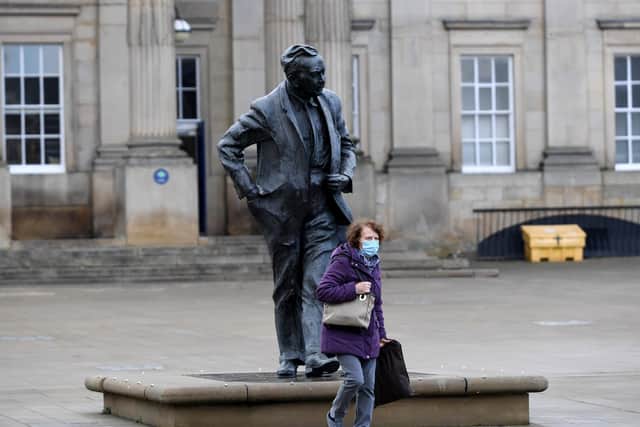 Huddersfield Town centre under lockdown, a woman walks past the Harold Wilson Statue outside Huddersfield Railway Station. Photo: Simon Hulme