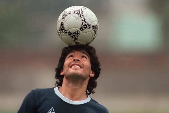 Argentine soccer star Diego Maradona, wearing a diamond earring, balances a soccer ball on his head as he walks off the practice field following the national selection's 22 May 1986 practice session in Mexico City. (Picture: JORGE DURAN/AFP via Getty Images)