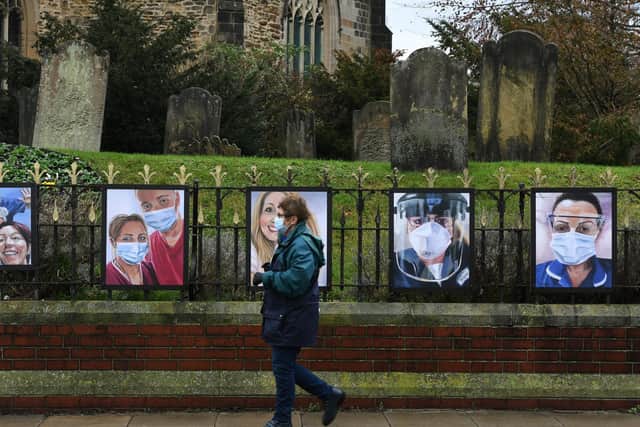 A woman walks past paintings of NHS workers, on the railings of All Saints Church in Pocklington.