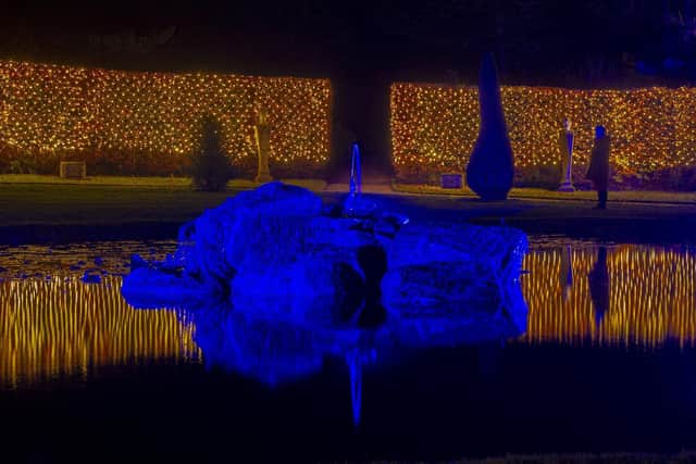 The festive light installation at Chatsworth House. A visitor takes in the illuminated ring pond.