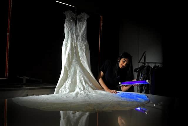 An apprentice at Bradford-based Christeyns examines a wedding dress.