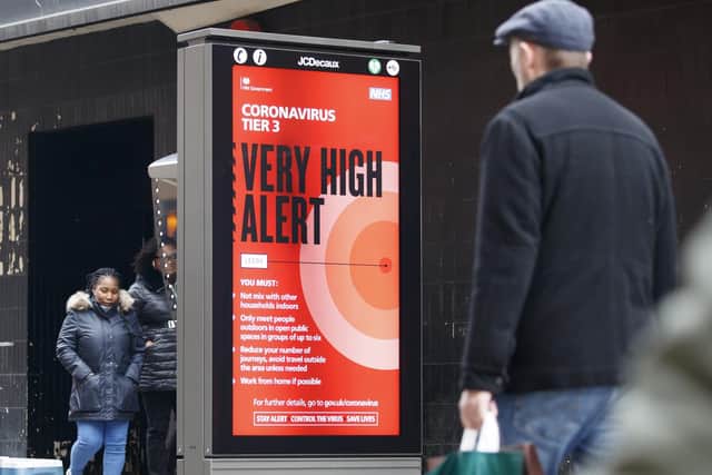 Christmas shoppers walk past a Coronavirus Tier 3 Very High Alert sign in Leeds, Yorkshire. Photo: PA