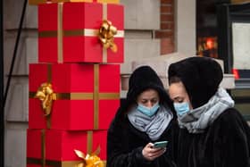 Two women wearing face masks with Christmas decorations in Covent Garden in London
