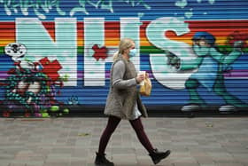A pedestrian wearing a face mask walks past a mural praising the NHS.