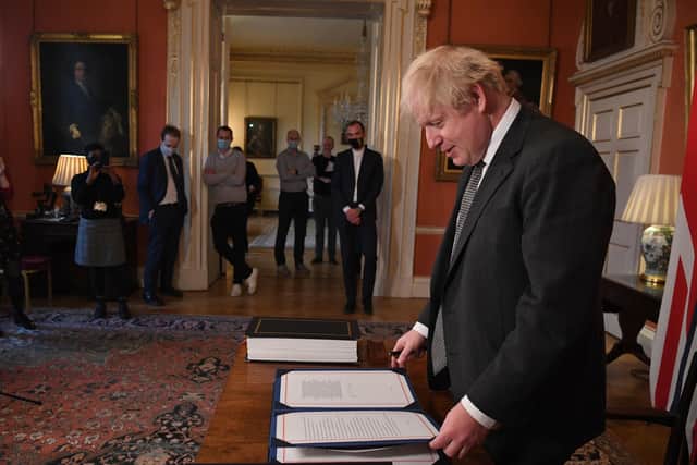 Prime Minister Boris Johnson prepares to sign the EU-UK Trade and Cooperation Agreement at 10 Downing Street after Wednesday's Parliamentary vote. Photo: PA/Leon Neal