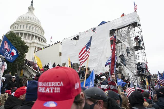 Supporters of President Donald Trump climb on an inauguration platform on the West Front of the U.S. Capitol.
