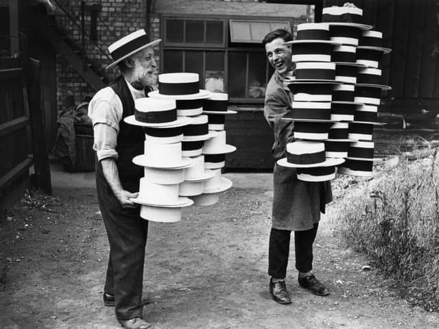 circa 1928:  Workers at a hat manufacturers in Luton carrying piles of men's straw hats, which were in demand due to a heatwave.  (Photo by Topical Press Agency/Getty Images)