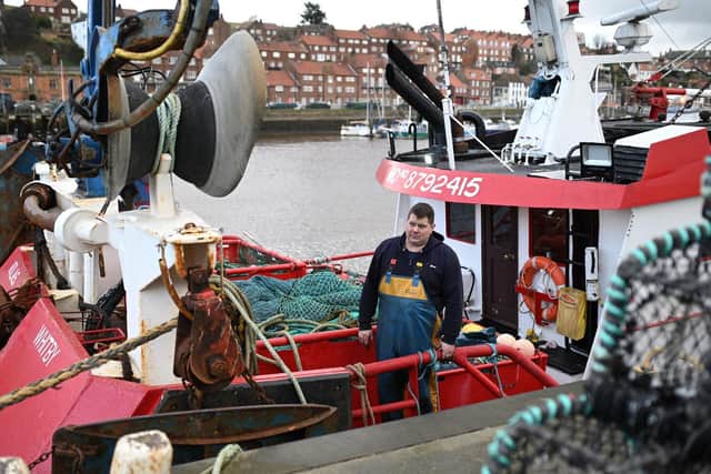 Skipper Richard Brewer stands aboard his fishing boat moored in the harbour at Whitby. Photo by OLI SCARFF/AFP via Getty Images.
