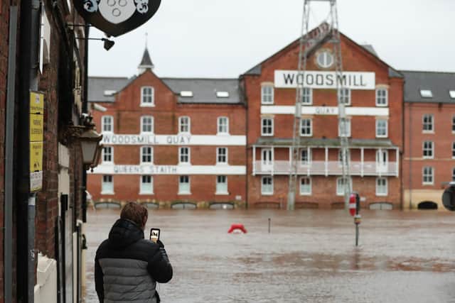 A person looking at their phone in front of floodwaters in York, ahead of Storm Christoph which is set to bring further flooding, gales and snow to parts of the UK. Heavy rain is expected to hit the UK, with the Met Office warning homes and businesses are likely to be flooded, causing damage to some buildings.  Photo: PA