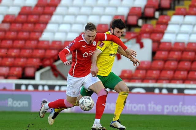 MARCHING ON: Barnsley's Cauley Woodrow is challenged by Norwich's Grant Hanley during Saturday's FA Cup win, in which Reds' goalkeeper Brad Collins had a very quiet day. Picture: Simon Hulme