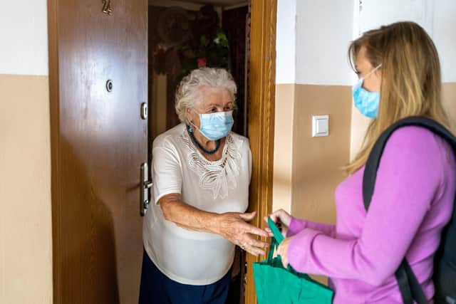 A young woman delivers groceries to an elderly lady during the lockdown.