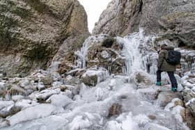 A walker examines a frozen waterfall at Gordale Scar